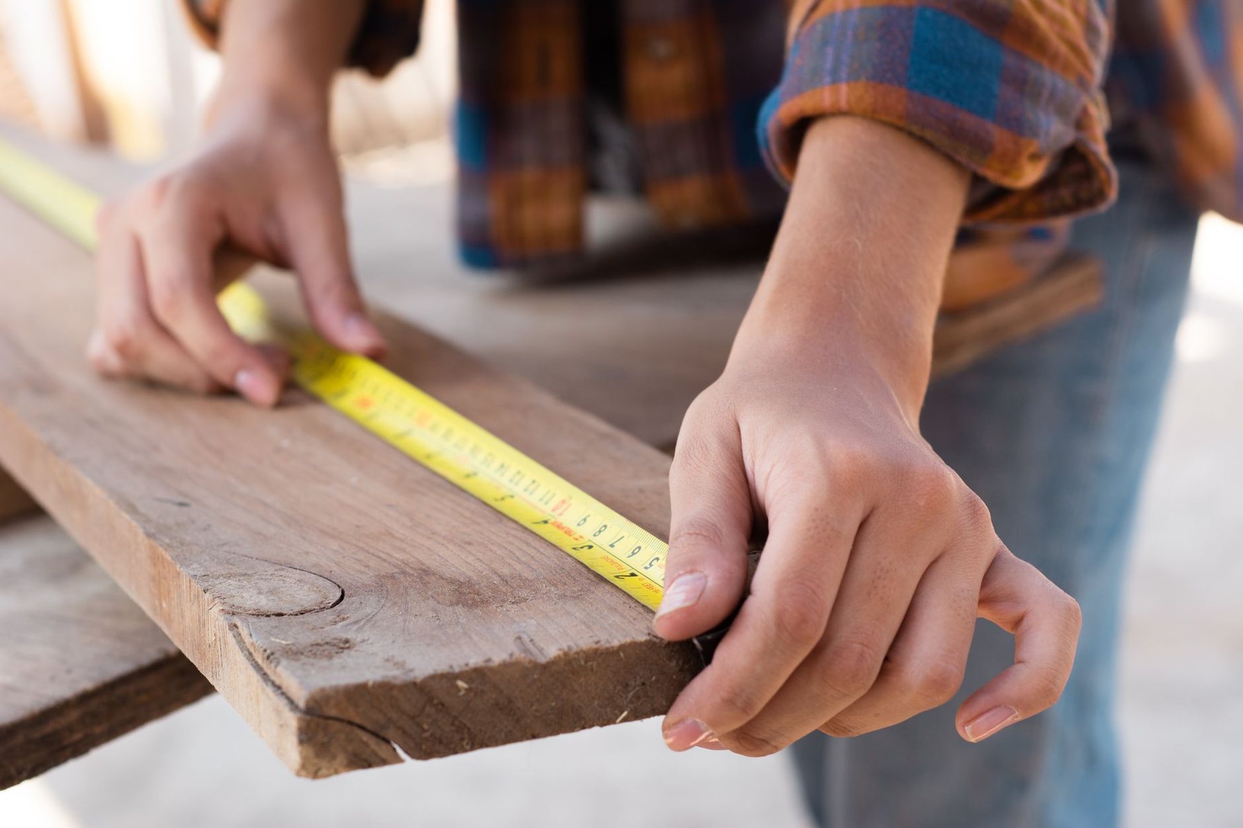 Medición de una pieza de madera con huincha antes de cortar